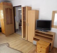 Nájomné bývanie v centre Serede - Obývacia izba v 2-izbovom byte s nábytkom a podlahou s dreveným dekorom.