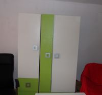 Nájomné bývanie v centre Serede - Šatníková skriňa s farebnými dverami a čierne kreslo v 2-izbovom byte.