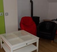 Nájomné bývanie v centre Serede - Obývacia izba v 2-izbovom byte s kreslami a stolíkom na podlahe s dreveným dekorom.