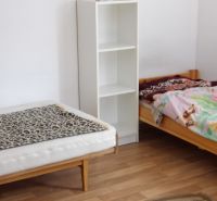 Nájomné bývanie v centre Serede - Dve postele, polička a podlaha s dreveným dekorom v 2-izbovom byte.