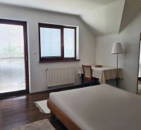 5-izb. dvojpodlažný rodinný dom, Rovinka - Spálňa v rodinnom dome so stolom, postelí a výhľadom cez veľké okná.