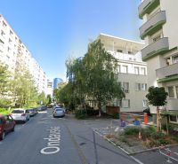 PRENÁJOM-  park. státie na Ondavskej ul. blízko zim. štadióna, BA II - Mestská ulica Ondavská 5 s parkovaním a zeleňou, v pozadí vysoká budova.