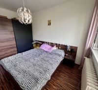 2 izbový byt na prenájom s balkónom na Kalinčiakovej, voľný od 01.10.2 - Spálňa v 2-izbovom byte s podlahou s dreveným dekorom, posteľou a skrinkou.