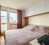 Kompletne zrekonštruovaný 3-izbový byt s priestranným balkónom - Spálňa s ružovou prikrývkou v 3-izbovom byte, vybavená podlahou s dreveným dekorom.