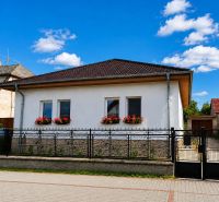 Na predaj zrekonštruovaný 4-izbový rodinný dom v Šalgočke  - Rodinný dom v Šalgočke s bielou fasádou, okennými kvetmi a valbovou strechou.