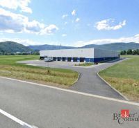 Investičná príležitosť: Komerčný pozemok 8 861 m² s platnou ÚPI v Hlin - Komerčné pozemky v Hliníku nad Hronom s priemyselnou halou, obklopené kopcovitou krajinou.