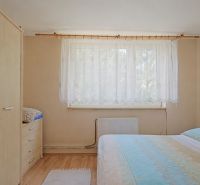 TOP - Rodinný dom v mestskej časti mesta BYTČA - Spálňa s posteľou, skriňou a podlahou s dreveným dekorom v rodinnom dome.