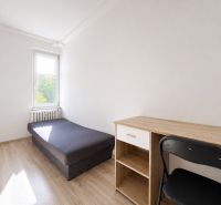 Na prenájom zariadený 4-izbový byt s balkónom I Ružinov |  - Izba s posteľou, stolom, stoličkou a podlahou s dreveným dekorom v 4-izbovom byte.