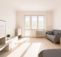 Na prenájom zariadený 4-izbový byt s balkónom I Ružinov |  - Svetlá obývačka s pohovkou, konferenčným stolíkom a podlahou s dreveným dekorom v 4-izbovom byte.