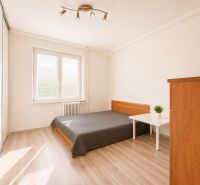 Na prenájom zariadený 4-izbový byt s balkónom I Ružinov |  - Spálňa v 4-izbovom byte s posteľou, skriňou a podlahou s dreveným dekorom.