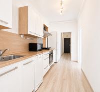 Na prenájom zariadený 4-izbový byt s balkónom I Ružinov |  - Kuchyňa v 4-izbovom byte s podlahou s dreveným dekorom a vstavanými spotrebičmi.