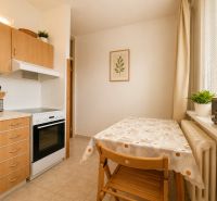 Pekný zariadený 3-izbový byt s 2 balkónmi | 85,3 m² | Petržalka I - Kuchyňa v 3-izbovom byte s dreveným dekorom a jedálenským stolom pri okne.