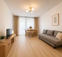 Pekný zariadený 3-izbový byt s 2 balkónmi | 85,3 m² | Petržalka I - Obývacia izba s podlahou s dreveným dekorom, sedačkou a jedálenským stolom v 3-izbovom byte.