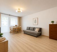 Pekný zariadený 3-izbový byt s 2 balkónmi | 85,3 m² | Petržalka I - Obývačka v 3-izbovom byte s podlahou s dreveným dekorom, pohovkou a jedálenským stolom.
