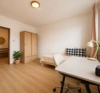 Pekný zariadený 3-izbový byt s 2 balkónmi | 85,3 m² | Petržalka I - Izba v 3-izbovom byte s podlahou s dreveným dekorom, stolom, posteľou a skrinkou.