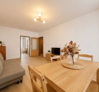 Pekný zariadený 3-izbový byt s 2 balkónmi | 85,3 m² | Petržalka I - Obývačka v 3-izbovom byte s podlahou s dreveným dekorom, jedálenským stolom a pohovkou.