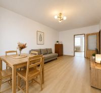 Pekný zariadený 3-izbový byt s 2 balkónmi | 85,3 m² | Petržalka I - Obývačka v 3-izbovom byte s podlahou s dreveným dekorom a jednoduchým nábytkom.