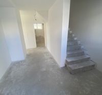 Ponúkame na predaj Rodinný dom v Rovinke na Platanovej ulici - Schodisko a chodba v rozostavanom rodinnom dome s betónovými podlahami a bielymi stenami.
