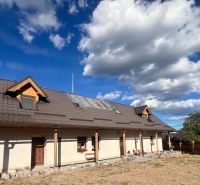 Atraktívny rodinný dom s veľkým pozemkom  – Hronská Dúbrava - Rodinný dom v Hronskej Dúbrave s veľkou strechou a skalnatým chodníkom v záhrade.