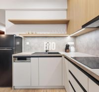DOWNTOWN NA DOSAH – DIZAJNOVÝ 1-izbový apartmán s loggiou a výhľadom n - Kuchyňa v 1-izbovom byte s podlahou s dreveným dekorom a čiernou chladničkou.