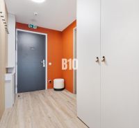 DOWNTOWN NA DOSAH – DIZAJNOVÝ 1-izbový apartmán s loggiou a výhľadom n - Vstupná hala 1-izbového bytu s podlahou s dreveným dekorom a oranžovou stenou.