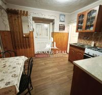 Rodinný dom 4 - izbový, Bódvaszilas, Maďarsko - Kuchyňa v rodinnom dome s podlahou s dreveným dekorom, jedálenským stolom a kuchynskou linkou.