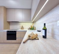 Moderný 3 izbový byt s balkónom a výhľadom na Zobor - Chrenová - Kuchyňa v 3-izbovom byte s vínom, chlebom a podlahou s dreveným dekorom.