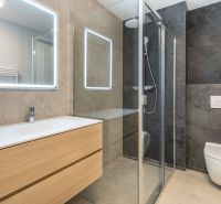 NOVOSTAVBA- NÍZKOENERGETICKÝ4 IZB.RODINNÝ DOM- LORINČÍK HÁJE-PREDAJ-KE - Kúpeľňa s dreveným nábytkom, sprchovacím kútom a veľkým zrkadlom v rodinnom dome.