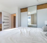 NOVOSTAVBA- NÍZKOENERGETICKÝ4 IZB.RODINNÝ DOM- LORINČÍK HÁJE-PREDAJ-KE - Spálňa v rodinnom dome s veľkou vstavanou skriňou a posteľou v svetlých farbách.
