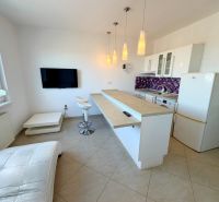 Na predaj kompletne prerobený 1 izbový byt, Vráble - Lúky, 36m2, 7/7 - Kuchyňa v 1-izbovom byte s barovými stoličkami a fialovým obkladom na stene.