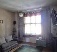 Na predaj 2 izbový tehlový byt 45m2 - Nové Zámky  - Obývacia izba v 2-izbovom byte s pohovkou, TV a podlahou s dreveným dekorom.