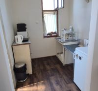 Na predaj 2 izbový tehlový byt 45m2 - Nové Zámky  - Kuchyňa v 2-izbovom byte s podlahou s dreveným dekorom a jednoduchým vybavením.