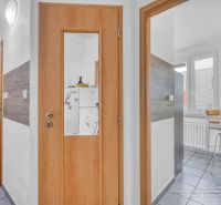 Moderný 2-izbový byt v Trnave na Jiráskovej ulici - Interiér 2-izbového bytu s drevenými dverami a preskleným vstupom do kuchyne.