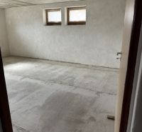 Rozostavaný rodinný dom Plavnica - Nevybavená miestnosť v rodinnom dome s dvoma malými oknami a surovou podlahou.