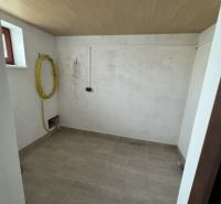 Rozostavaný rodinný dom Plavnica - Miesto pre práčovňu s obkladanou podlahou a stropom s dreveným dekorom v rodinnom dome.