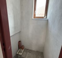 Rozostavaný rodinný dom Plavnica - Malá miestnosť s oknom v rodinnom dome, nefarbené steny, dlažba na podlahe.