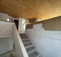 Rozostavaný rodinný dom Plavnica - Interiér rodinného domu so schodiskom, bielymi stenami a OSB doskami na strope.