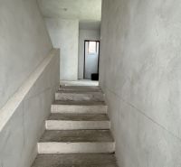 Rozostavaný rodinný dom Plavnica - Betónové schody vedúce na poschodie v rodinnom dome s omietnutými stenami.