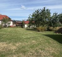 Rozostavaný rodinný dom Plavnica - Záhrada pred rodinným domom v Plavnici, trávnatá plocha a zeleň pod belasou oblohou.