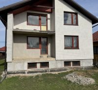 Rozostavaný rodinný dom Plavnica - Rodinný dom v Plavnici s jednoduchou fasádou a novými oknami, s trávnatým pozemkom.