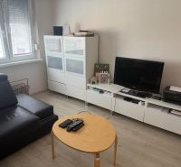 2,5 izbový byt v centre Lučenca - Obývacia izba v 2-izbovom byte s podlahou s dreveným dekorom a moderným nábytkom.