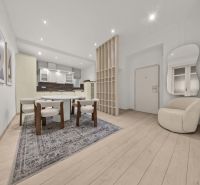  EXKLUZÍVNY, VEĽKOMETRÁŽNY 3i byt ( 130 m2 ), REKONŠTRUKCIA, CENTRUM - Interiér 3-izbového bytu s jedálenským stolom, kreslom a podlahou s dreveným dekorom.