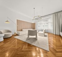 EXKLUZÍVNY, VEĽKOMETRÁŽNY 3i byt ( 130 m2 ), REKONŠTRUKCIA, CENTRUM - Obývacia izba s podlahou s dreveným dekorom, bielym nábytkom a veľkými oknami v 3-izbovom byte.