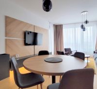ŠTÝLOVÝ 2i byt, PARKING, KLÍMA, PARKING, Čulenova ulica, SKY PARK - Obývačka 2-izbového bytu s podlahou s dreveným dekorom, stolom a sedačkou.