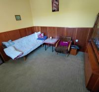 Rodinný dom Martin – Podháj, 5 izieb a pozemok 621 m² - Izba v rodinnom dome s pohovkou, kreslom a vitrínou, steny obložené drevom.