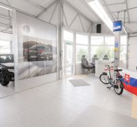 MODERNÝ, ZABEHNUTÝ, KOMPLETNE ZARIADENÝ AUTOSERVIS, LOZORNO - Výrobné priestory s vystavenými automobilmi, bicyklom a slovenskou vlajkou.