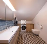 Priestranný 5-izbový rodinný dom (190 m²) s krásne upraveným 13a pozem - Kúpeľňa v rodinnom dome s práčkou, zrkadlom a umývadlom, geometrická dlažba.