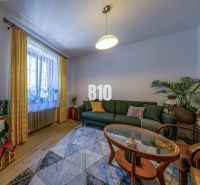Priestranný 5-izbový rodinný dom (190 m²) s krásne upraveným 13a pozem - Obývacia izba v rodinnom dome s pohovkou, kobercom a podlahou s dreveným dekorom.