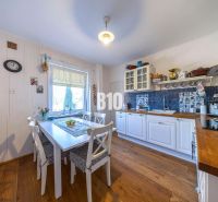 Priestranný 5-izbový rodinný dom (190 m²) s krásne upraveným 13a pozem - Kuchyňa v rodinnom dome s bielym nábytkom a podlahou s dreveným dekorom.