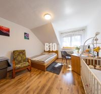 Priestranný 5-izbový rodinný dom (190 m²) s krásne upraveným 13a pozem - Spálňa v rodinnom dome s posteľou, detskou postieľkou a podlahou s dreveným dekorom.